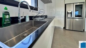 A modern kitchen with a stainless steel sink, a faucet, a bottle of liquid dish soap, and a water dispenser. - Villa Ciste - 12/15pers - Heated swimming pool - Panoramic mountain view - (Zonza)