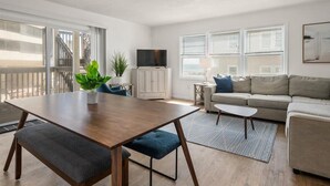 Una sala de estar moderna con una mesa de comedor de madera, un sofá y un televisor.