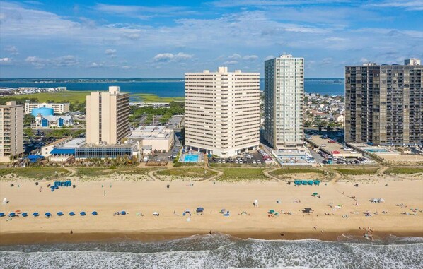 Un paisaje urbano costero con rascacielos, una playa y un puerto deportivo.