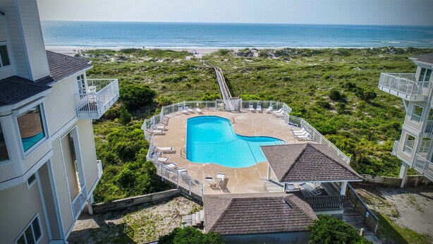 Una piscina envoltada de gandules i una vista de l'oceà.