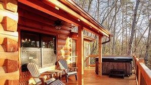 A wooden deck with Adirondack chairs, a hot tub, and a glass door leading to a covered porch. - Gated Community, Hot Tub, Game Room (Lake Lure)