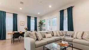 Ein modernes Wohnzimmer mit Sofa, Couchtisch und Essbereich.