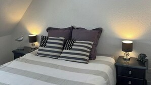 Ein ordentlich eingerichtetes Schlafzimmer mit einem Bett, zwei Nachttischen und zwei Lampen.