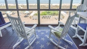 Un balcon avec des fauteuils à bascule blancs et une vue sur la plage.