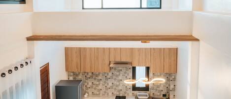 Cozinha moderna com armários de madeira, bancada de mármore e área de jantar com mesa posta para quatro pessoas.