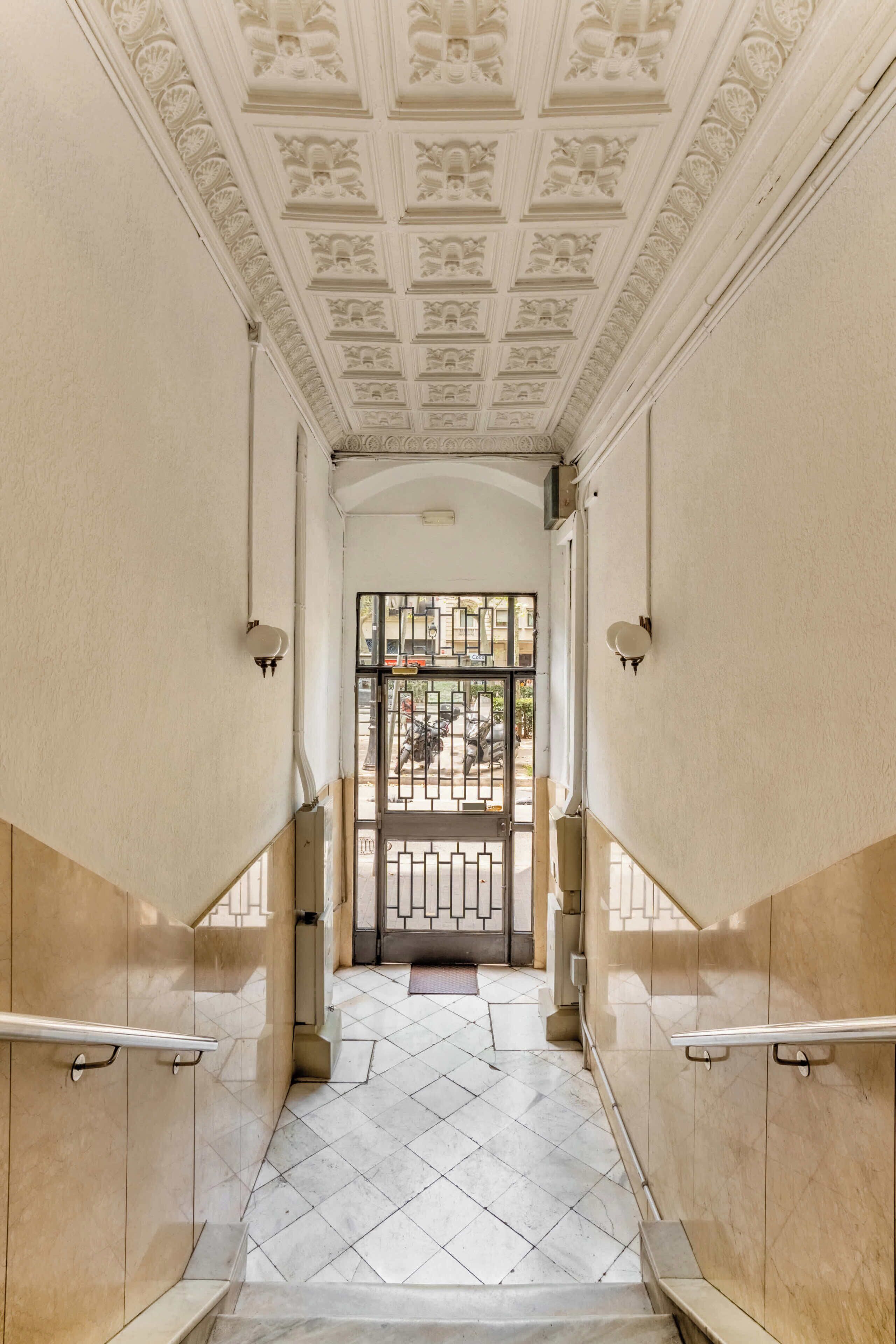 A hallway with a tiled floor, a decorative ceiling, and a gated entrance.