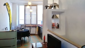 Un espace de vie compact comprenant un coin repas, une cuisine et un petit coin salon.