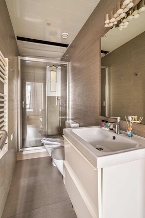 A modern bathroom with a large bathtub, a glass-enclosed shower, and a large mirror. - Beautiful 4bd 4ba apartment in Eixample District (Barcelona)