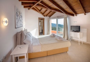 Ein Schlafzimmer mit Bett, Fernseher, Schreibtisch und Fenster mit Blick.