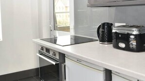 Ett modernt kök med vitvaror i rostfritt stål, en inbyggd ugn och en kaffebryggare.