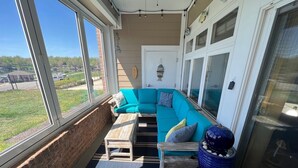 A sunlit patio with a turquoise sofa, a wooden table, and a blue vase. - #303 Pointe - 2 Bedroom Lakefront Condo at Mariners SML (Bedford County)