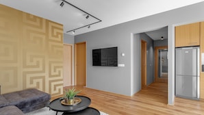 A modern living room with a sectional sofa, a round coffee table, and a flat-screen TV mounted on the wall. - Luxury's 2 Bedroom Apartment in Downtown Reykjavik with Included parking (Reykjavík)
