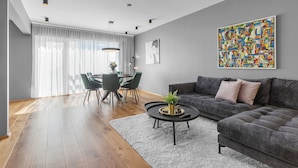 A modern living room with a grey sofa, a round coffee table, and a dining area with a table and chairs. - Luxury's 2 Bedroom Apartment in Downtown Reykjavik with Included parking (Reykjavík)