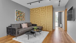 A modern living room with a grey sofa, two black coffee tables, a white rug, and a colorful abstract painting on the wall. - Luxury's 2 Bedroom Apartment in Downtown Reykjavik with Included parking (Reykjavík)
