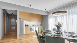 A modern kitchen with wooden cabinets, a built-in oven, and a dining area with a round table set for six. - Luxury's 2 Bedroom Apartment in Downtown Reykjavik with Included parking (Reykjavík)