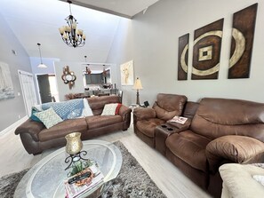 A spacious living room with two brown leather sofas, a glass coffee table, and a chandelier. - Spacious East of Eden Condo near Sandy Beach!! (Heber Springs)
