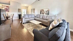 A modern living room with a sectional sofa, a coffee table, and a ceiling fan.