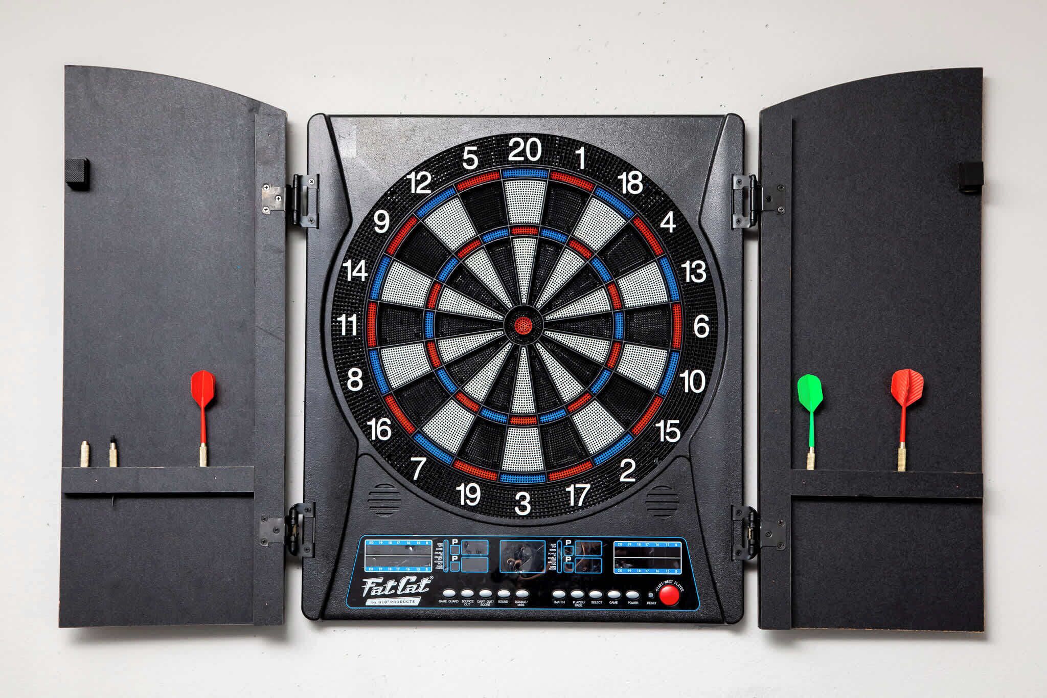 A dartboard mounted on a wall with two dartboards on either side.