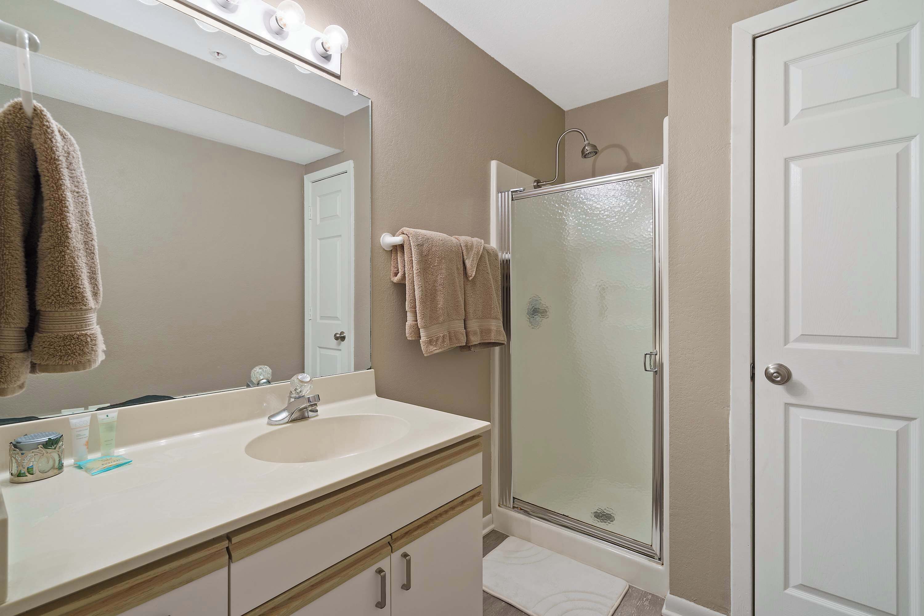 A bathroom with a sink, mirror, and shower.