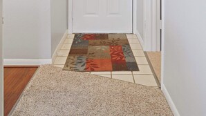 A hallway with a white door, a patterned rug, and a small green decoration on the wall. - Valley View Retreat - Holiday Hills Branson - Golf Resort -outdoor Pools (Branson)