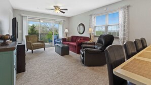 A spacious living room with a ceiling fan, a dining table with chairs, a red sofa, a brown armchair, and a black leather chair. - Valley View Retreat - Holiday Hills Branson - Golf Resort -outdoor Pools (Branson)