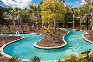 Une piscine au design sinueux, entourée de palmiers et d’autres plantes tropicales.