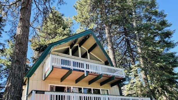 A two-story cabin with a balcony, surrounded by tall trees. - 3 bedroom dream home 🏡 Big Bear Lake CA / Running Springs/Lake Arrowhead. (Running Springs)
