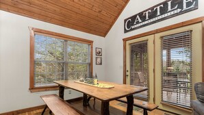 Una mesa de comedor de madera con bancos, techo de madera y una puerta con un letrero que dice 'CATTLE'.