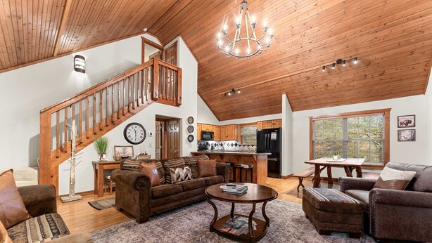 Un salón espacioso con una escalera de madera, una mesa de comedor y una zona de cocina.