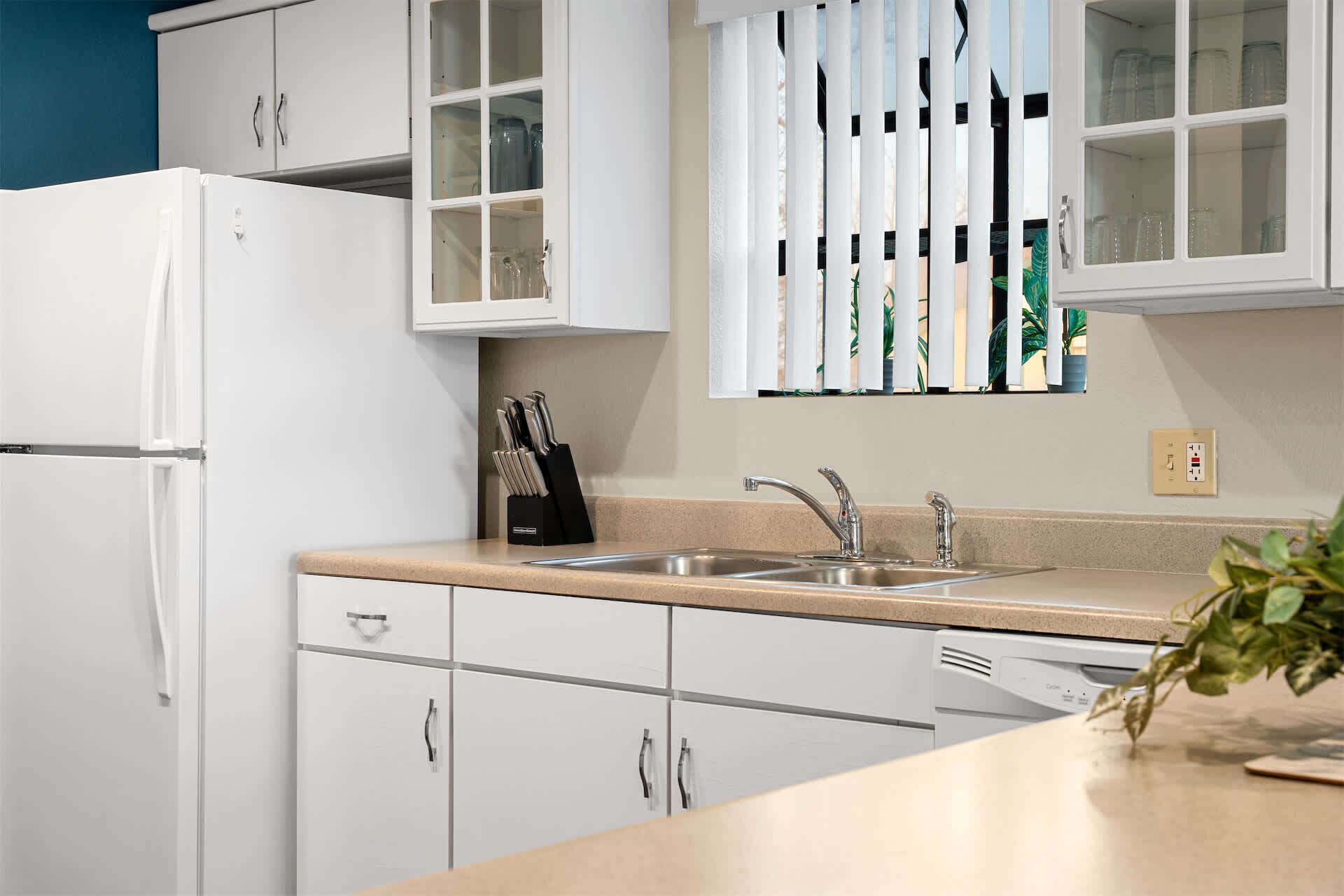 A kitchen with white cabinets, a stainless steel sink, and a dishwasher.