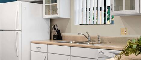 A kitchen with white cabinets, a stainless steel sink, and a dishwasher.