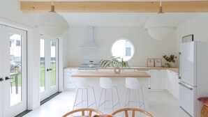 Une cuisine moderne avec des meubles blancs, un îlot central en bois et des tabourets de bar.