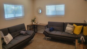 Een woonkamer met twee donkere banken, een salontafel en een bijzettafeltje met een lamp en een plant.