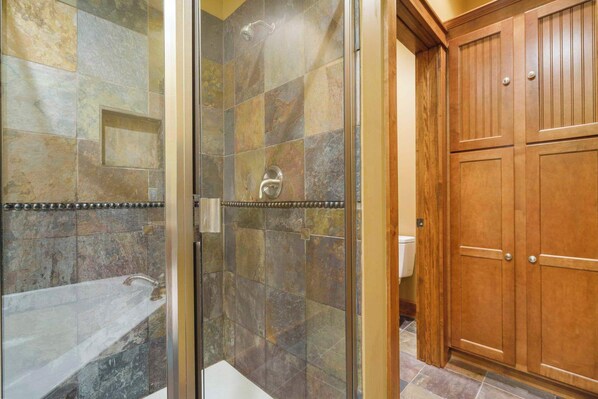 Une salle de bain avec une douche à parois de verre, une baignoire et des meubles en bois.