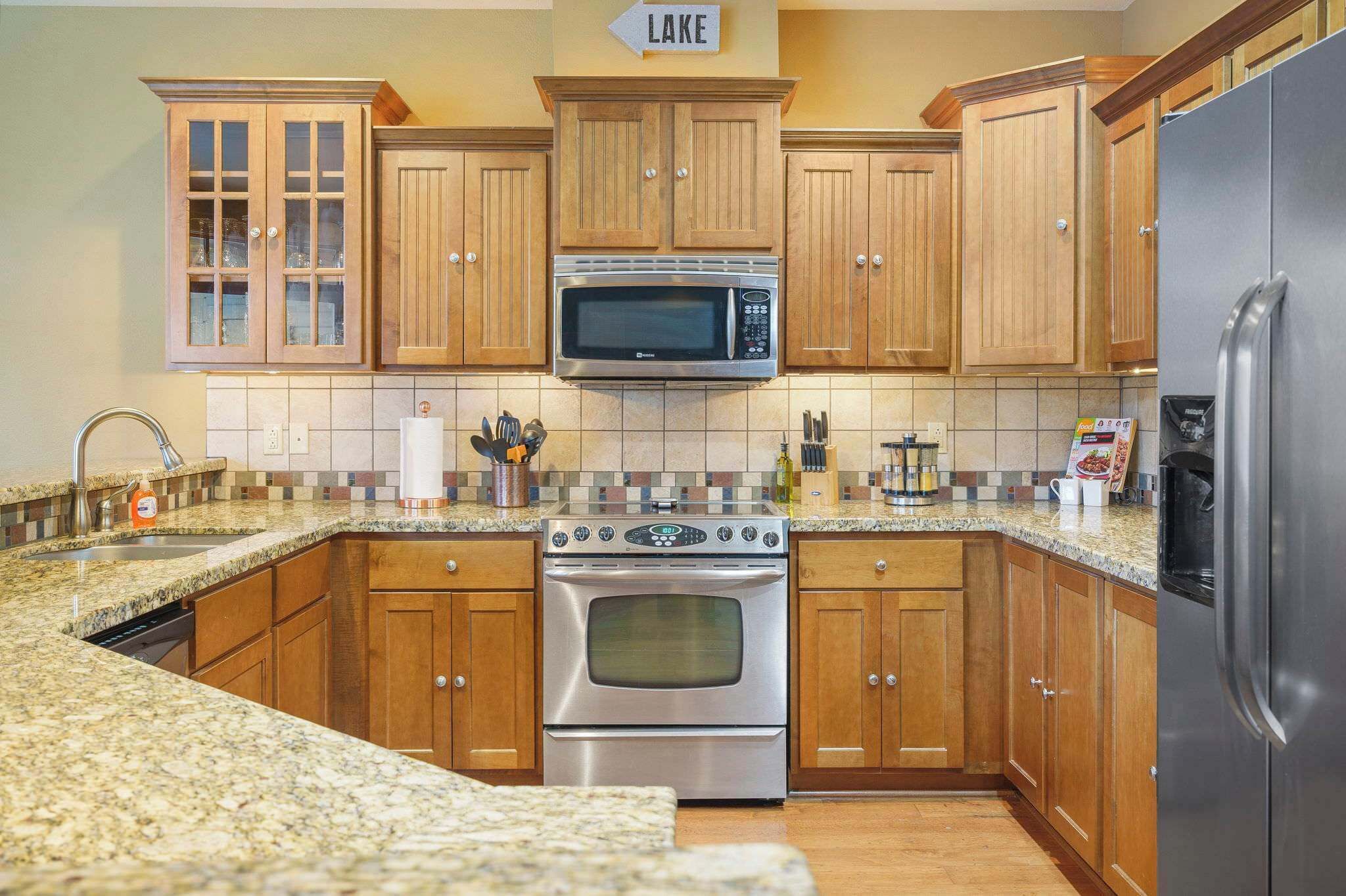 A kitchen with wooden cabinets, a stainless steel oven, a microwave, and a refrigerator.