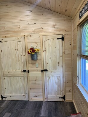 Een houten interieur met twee grote deuren, een klein raam en een bord boven het raam.