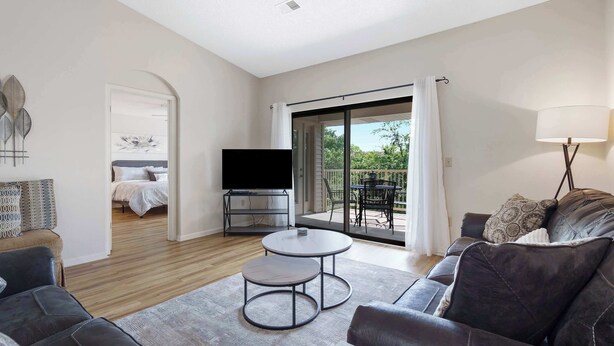 A modern living room with a sofa, two round tables, a TV, and a balcony with a view. - Skyline View at the Foothills (Branson)