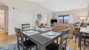 A dining area with a table set for four, a sofa, and a TV in the background. - Skyline View at the Foothills (Branson)