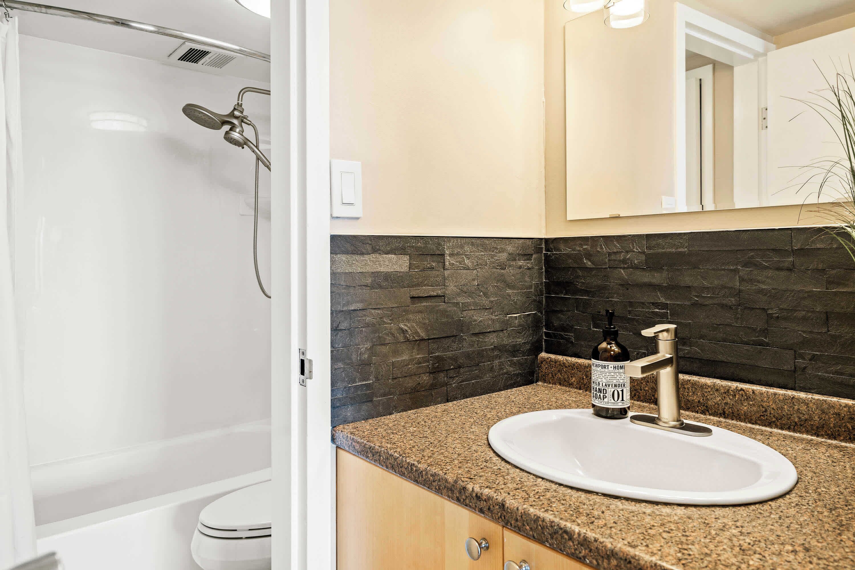 A bathroom with a shower, a sink, and a toilet.