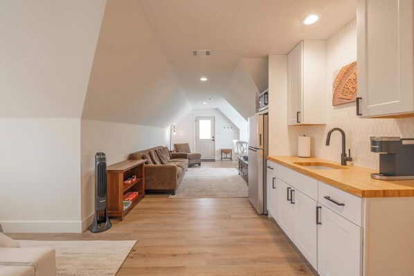 A modern kitchen with white cabinets, a wooden countertop, and a built-in coffee machine.