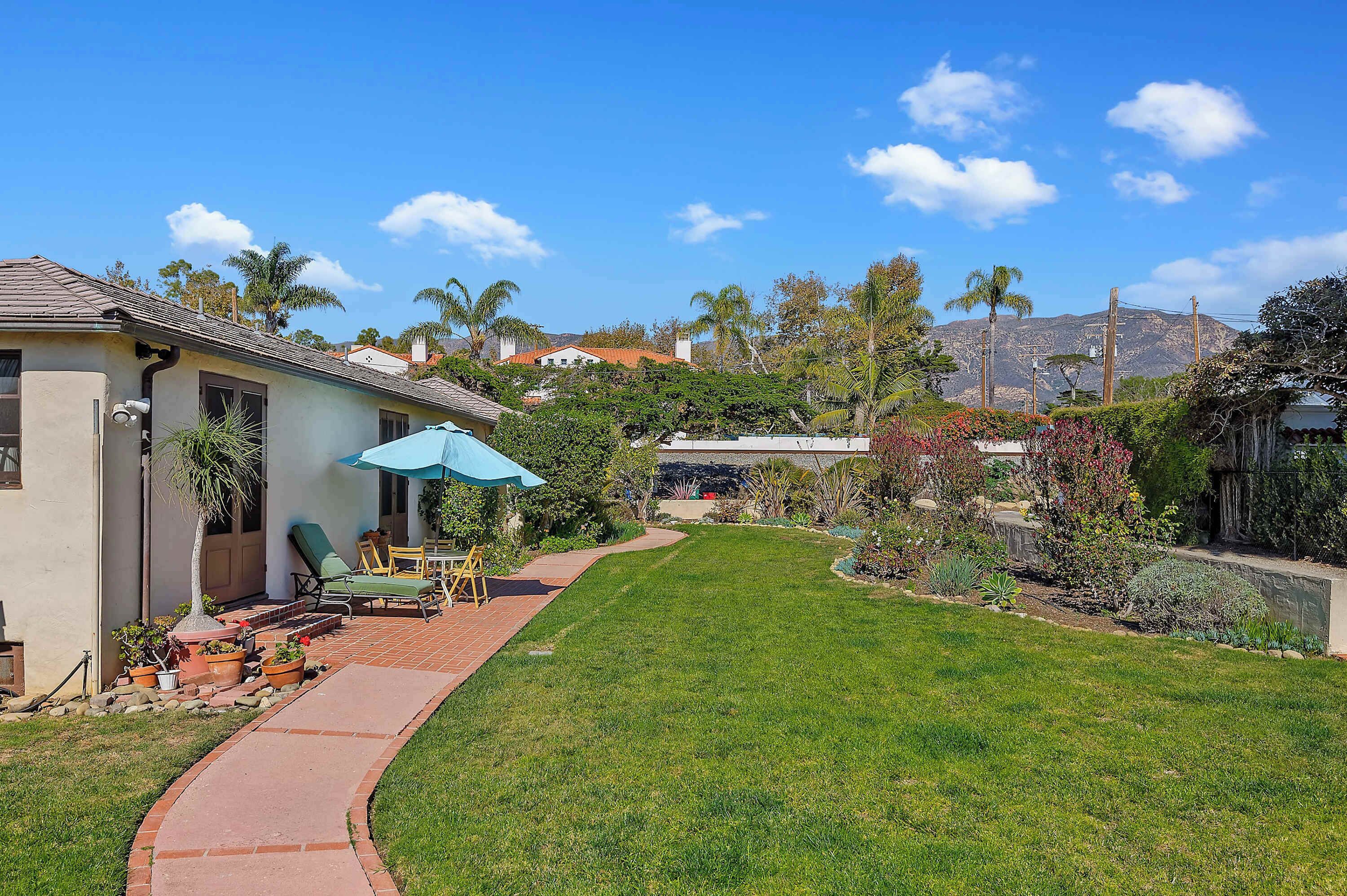 A residential property with a well-maintained lawn, patio furniture, and a clear view of a mountain in the background.