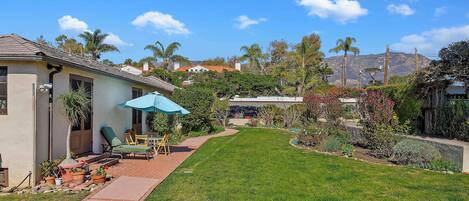 A residential property with a well-maintained lawn, patio furniture, and a clear view of a mountain in the background.