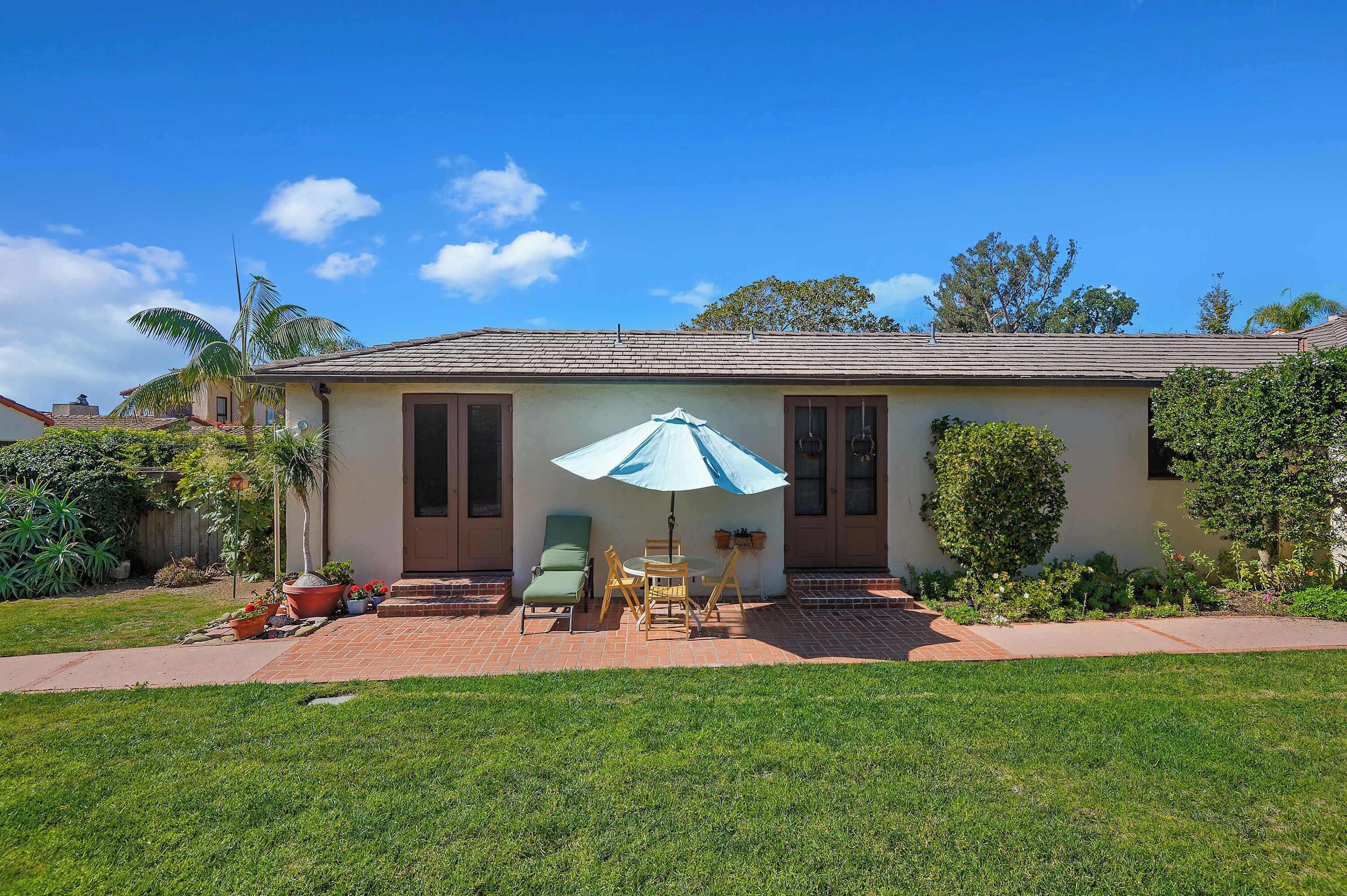 A house with a patio, a lawn, and a blue umbrella.