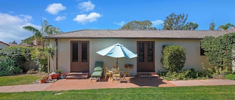 A house with a patio, a lawn, and a blue umbrella.
