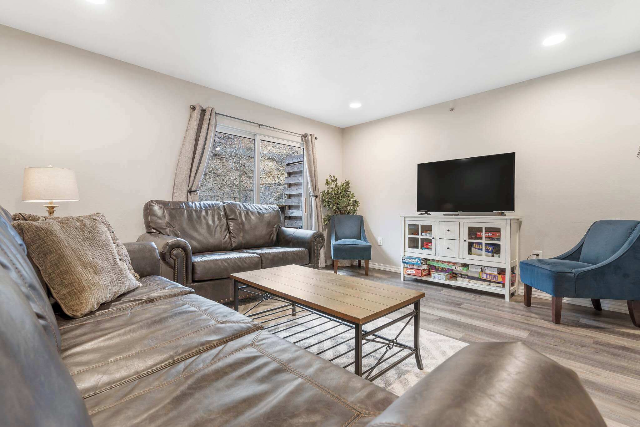 Una sala de estar con sofá, sillón, mesa de centro y televisor.