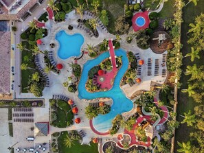 An aerial view of a resort with multiple swimming pools, sun loungers, and palm trees. - Rendezvous at Regal Palms (Davenport)