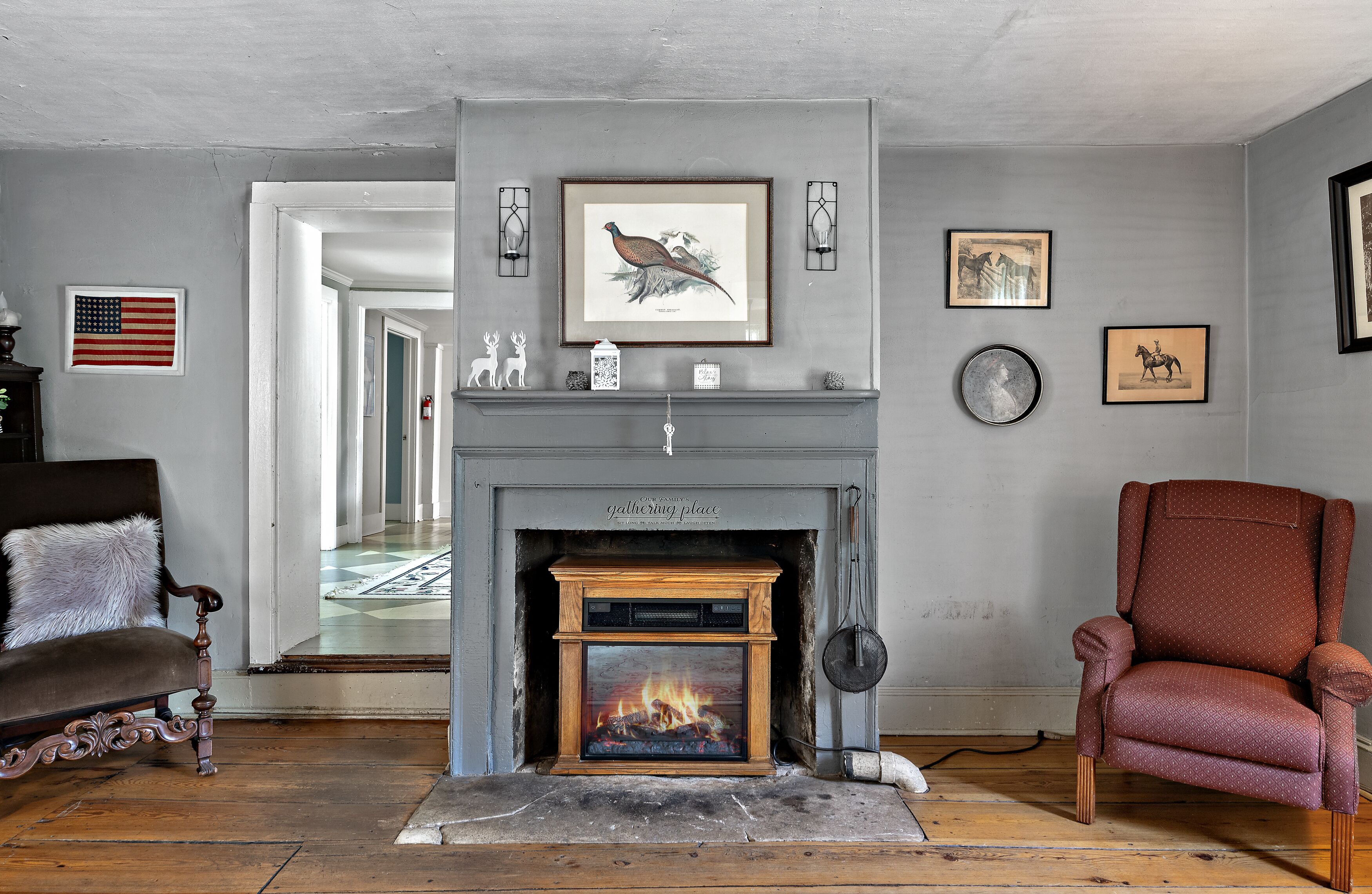 A living room with a fireplace, a sofa, a chair, and wall-mounted artwork.