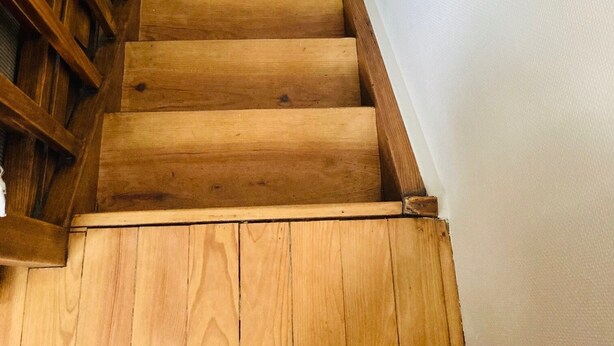 Un escalier en bois, doté d’une rampe, menant à un palier.