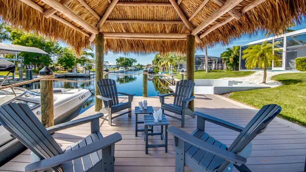 Een overdekt terras met Adirondack stoelen en een zwembad.