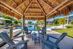 A covered deck with Adirondack chairs and a pool. - Villa Belle Isle - heated pool, south facing, cozy interior, close to river (Cape Coral)